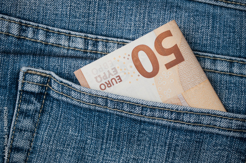 closeup of fifty euros banknote in blue jeans pocket photo