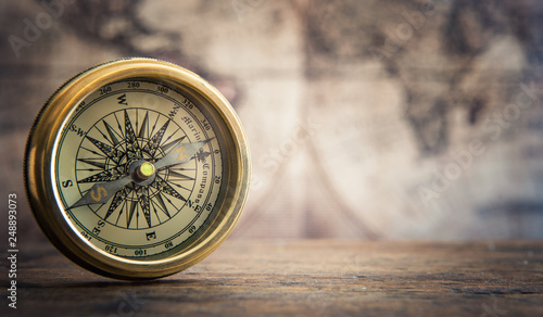 Old compass on vintage map background.