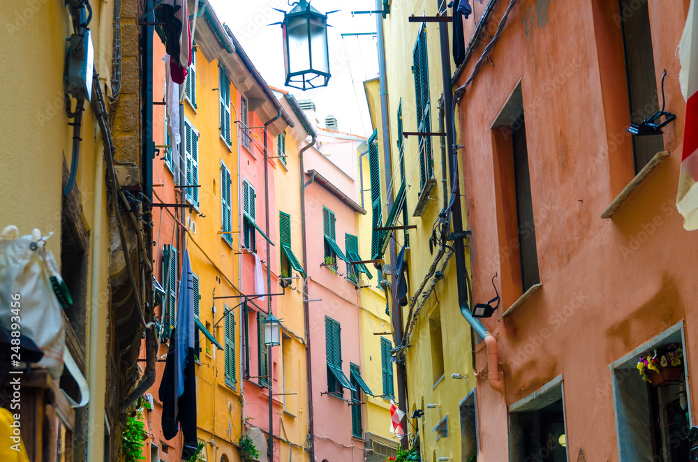 Narrow street with colorful multicolored buildings houses of Portovenere town village with street lamps, shutters on windows, National park Cinque Terre, La Spezia, Liguria, Italy