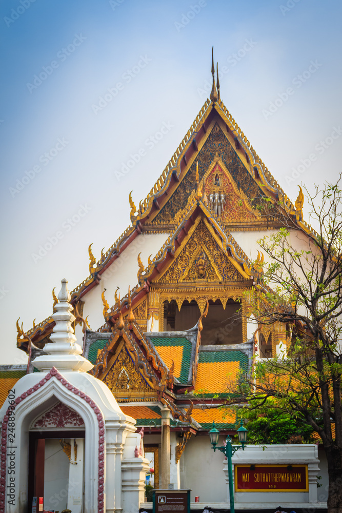 Fototapeta premium Beautiful roof gable and entrance gate of Wat Suthat temple, Thailand. Wat Suthat Thepphawararam is a royal temple of the first grade in Bangkok. Construction of the temple was completed in 1847.