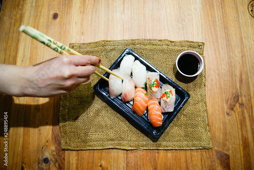 Hand of woman taking niguiris with japanese chopsticks photo