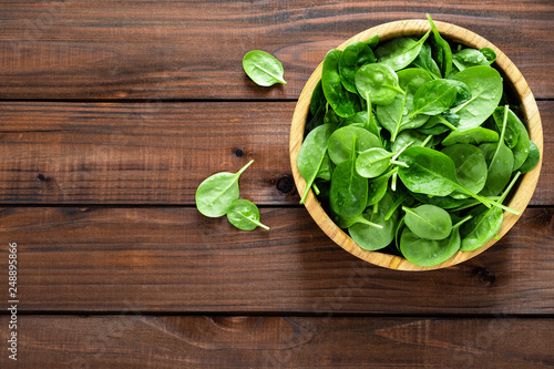Fresh spinach leaves on wooden background. Healthy vegan food. Top view.