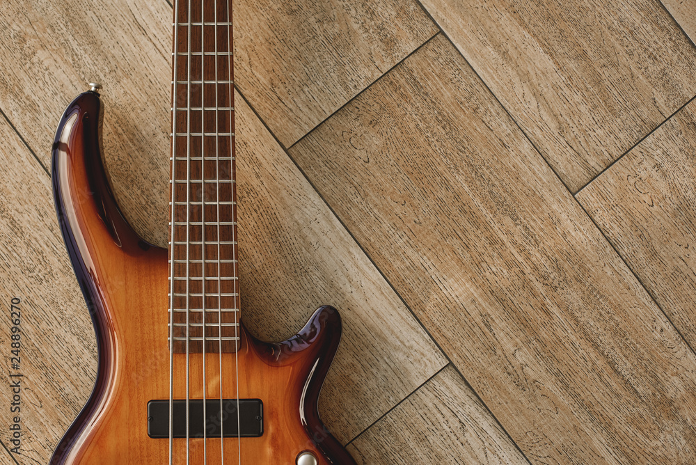 Power of musical instrument. Top view of the brown electric guitar lying on the wooden floor. Power of musical instrument. Top view of the brown electric guitar lying on the wooden floor.