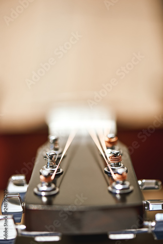 Uppermost part of the guitar. Vertical close-up photo of guitar mechanism for stringing guitar strings: tuning keys, gears