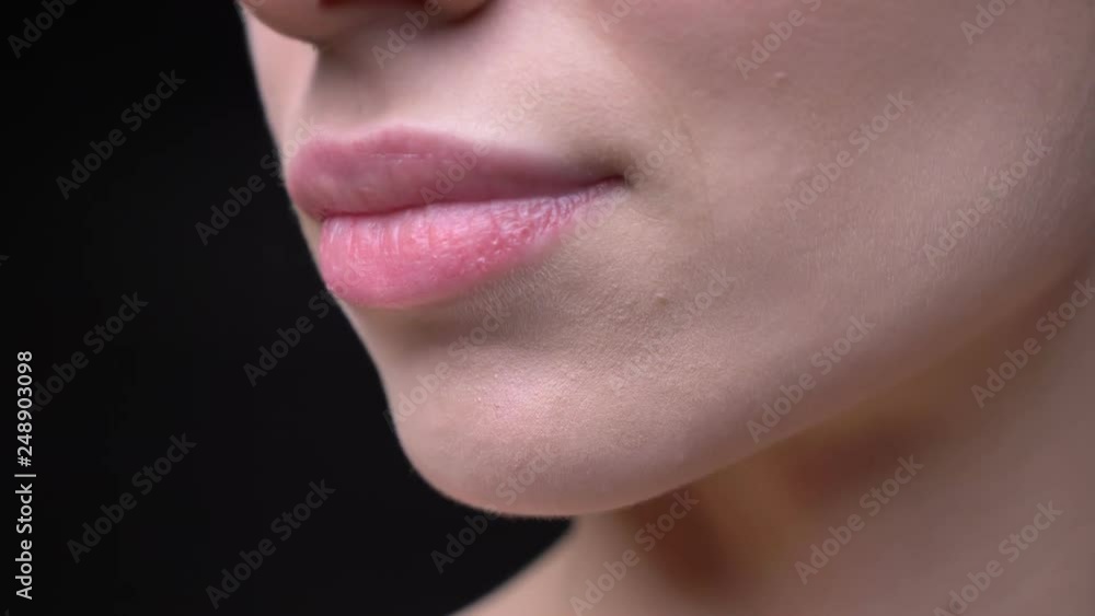 Close-up lips-portrait of young and slim caucasian girl with nude make-up moving on black background. Close-up lips-portrait of young and slim caucasian girl with nude make-up moving on black background.