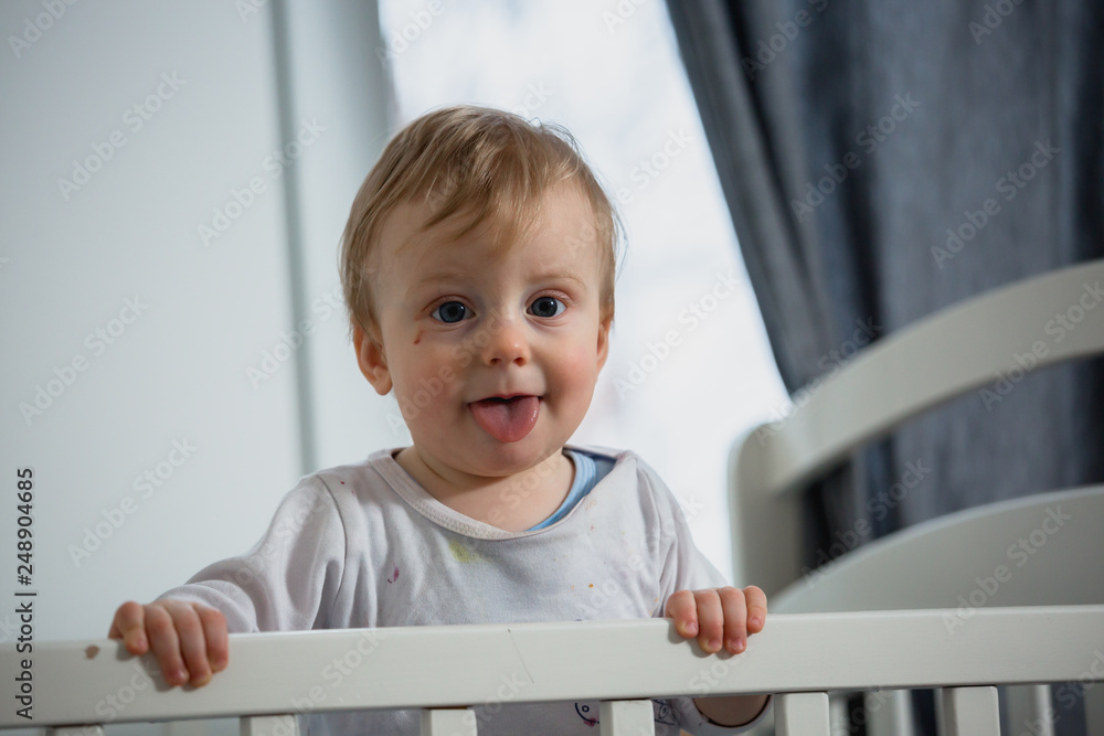baby boy standing in crib in his room baby boy standing in crib in his room
