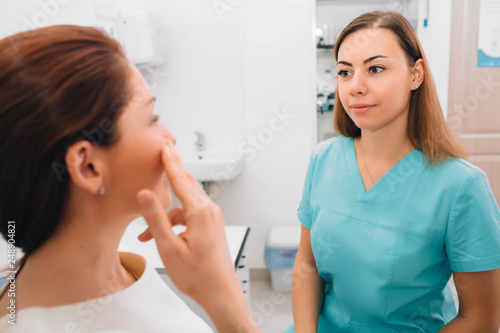 Doctor listens to the patient's complaints while the patient points to the maxillary sinuses. Sinusitis, symptoms.