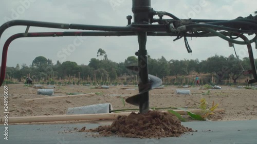 Close Up of Post hole digger or auger drilling sapling hole in Slow Motion photo