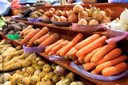 Carrots, onions, roots and other various vegetables are sold on market shelves