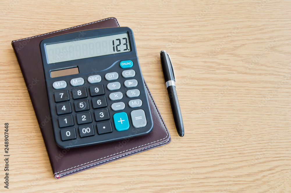 Calculator with a notepad and a ballpoint pen on a wooden table with Copy Space Calculator with a notepad and a ballpoint pen on a wooden table with Copy Space
