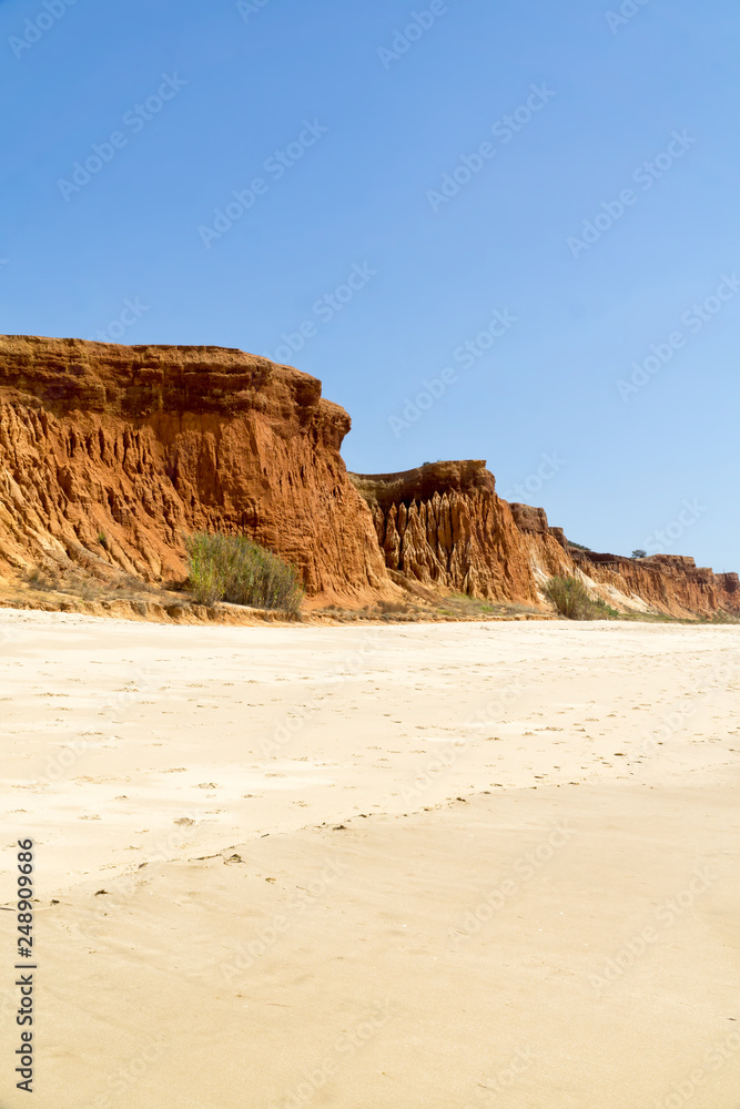 High cliffs along Falesia Beach and The Atlantic Ocean in Albufeira, Algarve, Portugal. Sunny summer day, blue sky. Vertical image.