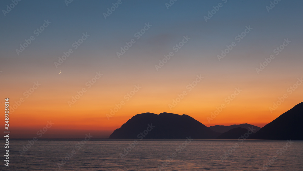 Sunset at sea on Greece seaside in summer with moon