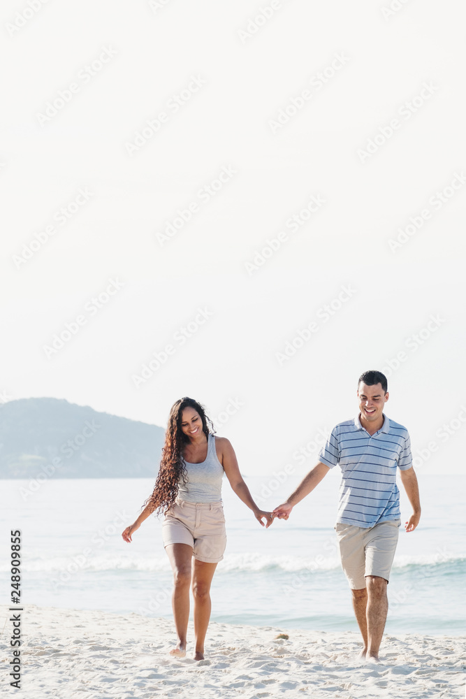 A Latin couple on vacation holding hands on the beach