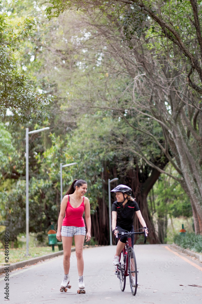 A woman cyclist and roller skater exercising and talking together in Ibirapuera park, Sao Paulo