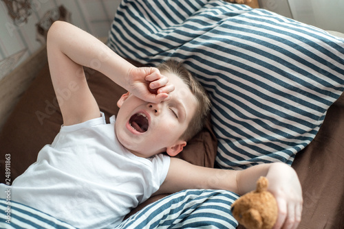 Close up face of Kid yawning and holding teddy bear, Sleepy child yawning and looking at cameta, Head shot tired child get a cold during weather change, Children health care concept photo