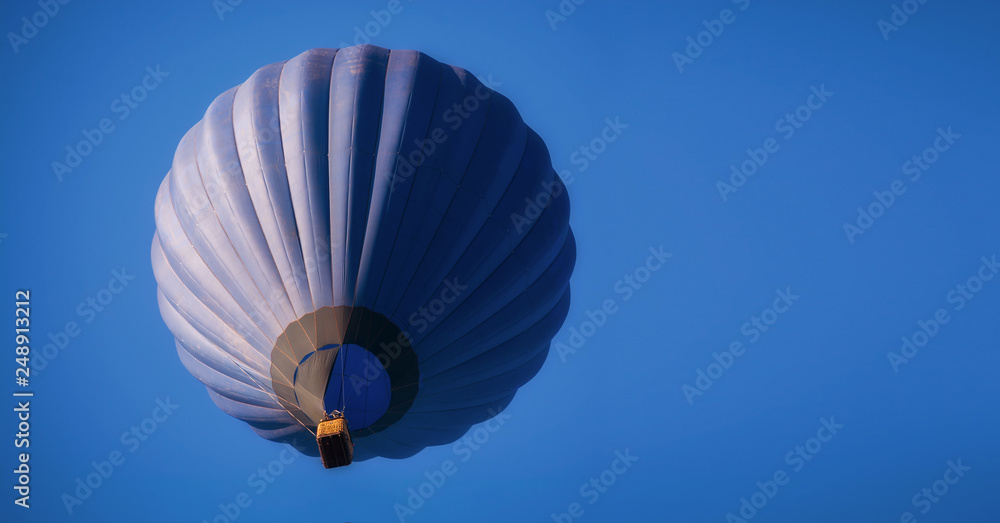 Fototapeta premium Dark blue balloon in the sky. Aerostat. People in the basket. Fun. Summer entertainment. Romantic adventures.