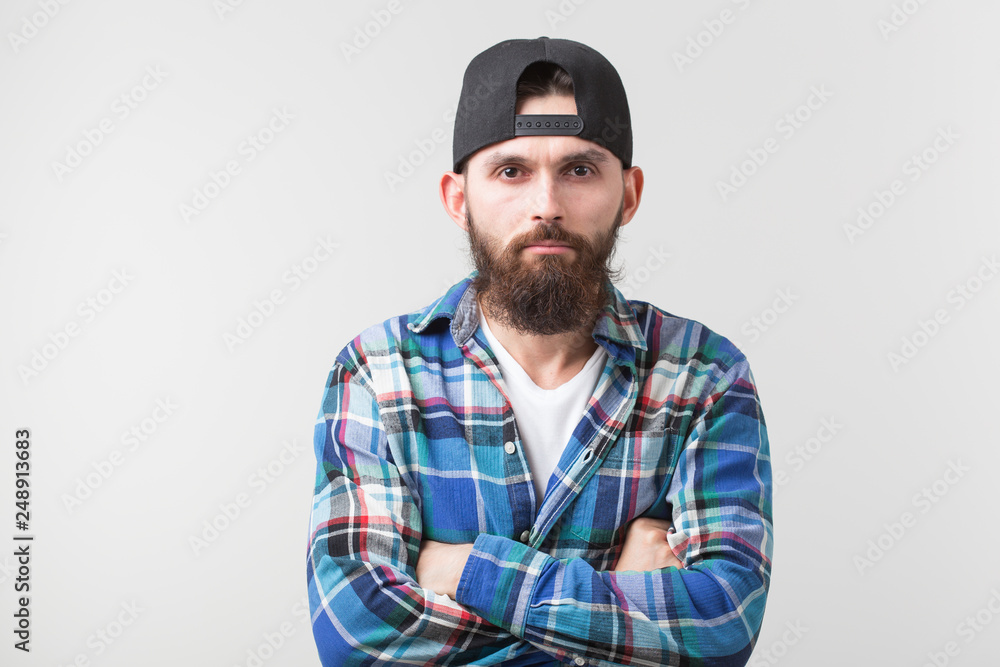 Hipster, lifestyle and people concept - Angry bearded man in a cap posing over the white background Hipster, lifestyle and people concept - Angry bearded man in a cap posing over the white background