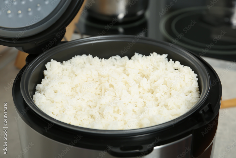 Modern cooker with fresh boiled rice in kitchen