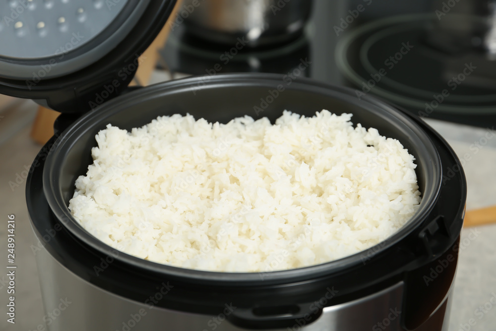 Modern cooker with fresh boiled rice in kitchen Modern cooker with fresh boiled rice in kitchen