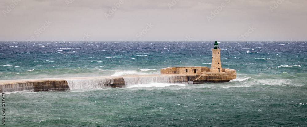 St. Elmo Breakwater and Lighthouse withstand raw sea and high waves. Valletta, Malta, Europe.