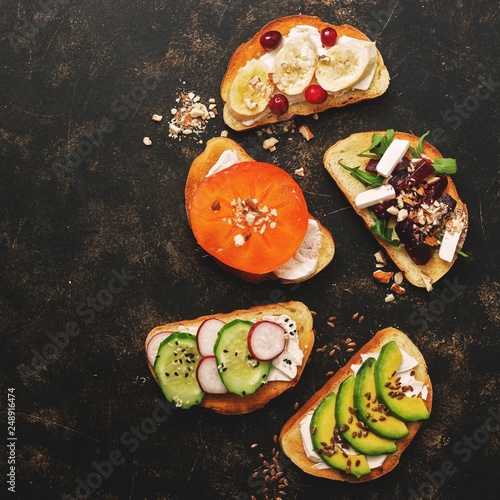 A variety of vegan sandwiches with vegetables and fruits on a dark rustic background. Top view, flat lay. The concept of healthy eating.