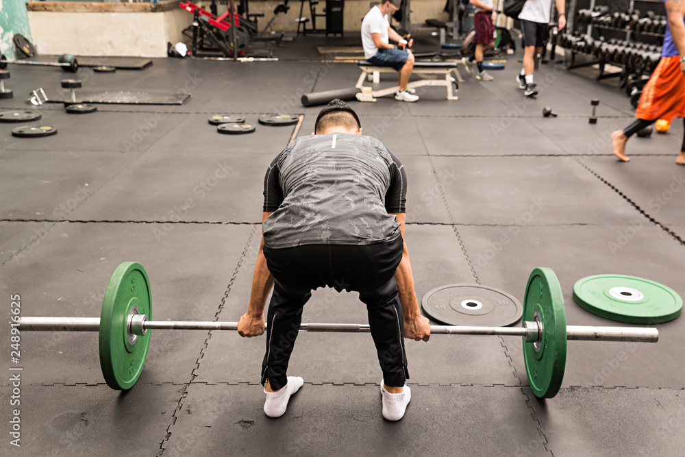 Hombre en gimnasio levantando pesas. Stock Photo