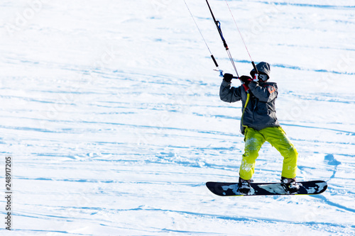 Snowboarder on a snowboard with snow kite is jimping above the fresh snow. Concept of outdoor extreme activities in winter snowkite photo