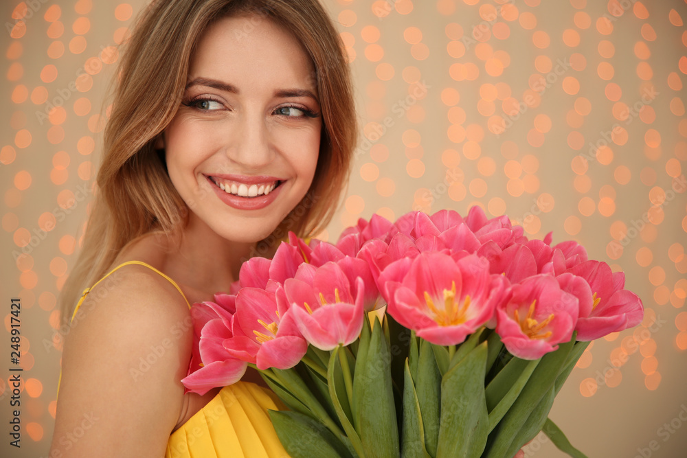 Portrait of smiling young girl with beautiful tulips on blurred background. International Women's Day Portrait of smiling young girl with beautiful tulips on blurred background. International Women's Day