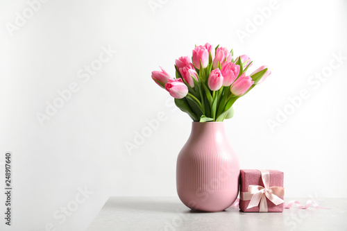 Fototapeta Naklejka Na Ścianę i Meble -  Bouquet of beautiful spring tulips in vase and gift box on table against white background. International Women's Day