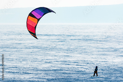 Snowboarder with bright multicolored snow kite on the fresh snow. Concept of outdoor extreme activities in winter snowkite