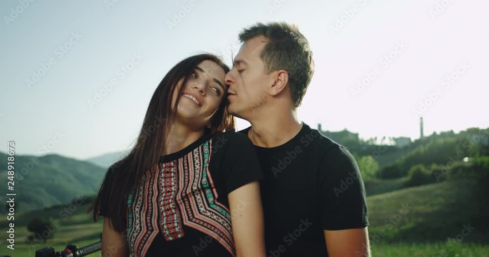 Romantic couple touching each other in the middle of nature behind of their retro motorcycle , spending a lovely time together Romantic couple touching each other in the middle of nature behind of their retro motorcycle , spending a lovely time together