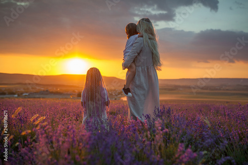 A young mother with two children looking at the outgoing sun in a lavender field