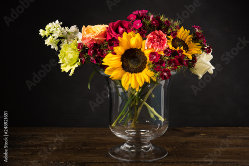 Bouquet of white yellow and red flowers in a vase on a dark background © Konstantin Maslak