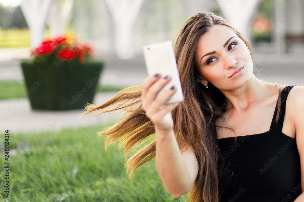 Beautiful young woman using phone and drink coffee sitting on the curb in the street. Beautiful young woman using phone and drink coffee sitting on the curb in the street.