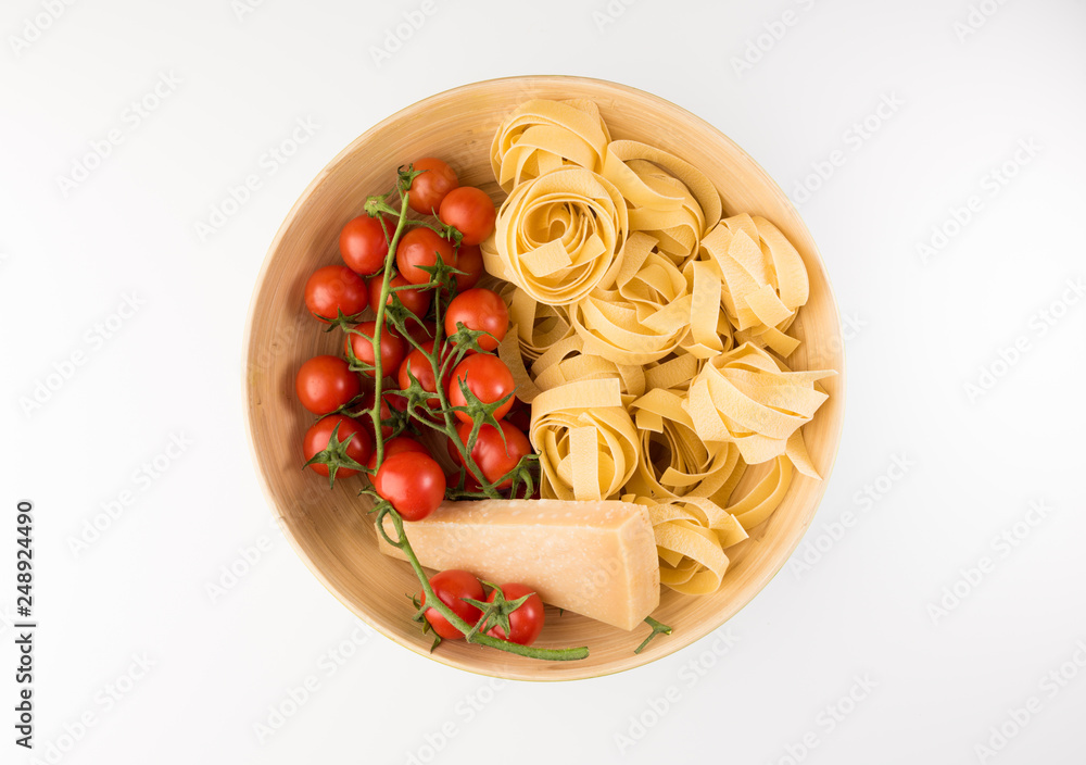 Bowl with raw pasta, tomatoes and parmesan cheese isolated on white background, top view. Flat lay Bowl with raw pasta, tomatoes and parmesan cheese isolated on white background, top view. Flat lay