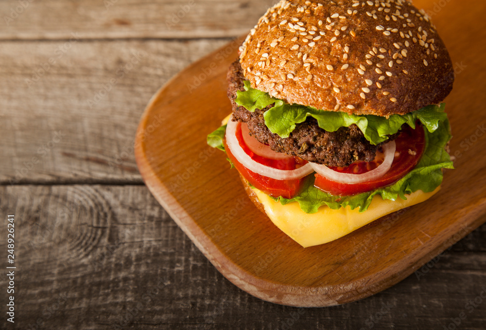 Tasty burger with cheese on wooden table Tasty burger with cheese on wooden table