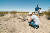 A girl making picture of a cactus on her phone while the rest of family is waiting for her in a Texas desert
