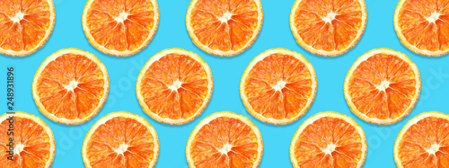 Dry orange slices horizontal pattern design. Cut fruit section isolated on blue background.