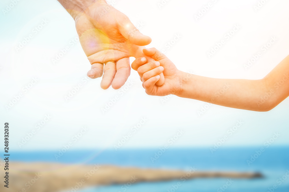 Beautiful hands of parent and child on sea background Beautiful hands of parent and child on sea background