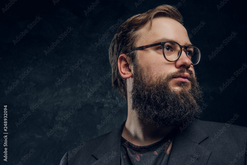 Portrait of a brutal hipster in glasses looking left on a black background in the studio Portrait of a brutal hipster in glasses looking left on a black background in the studio