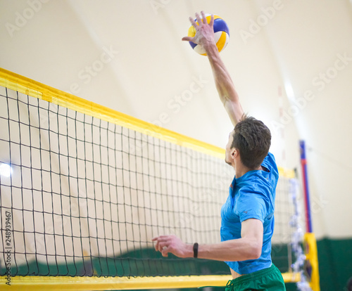 the guy is playing volleyball in a covered room with sand. handballs