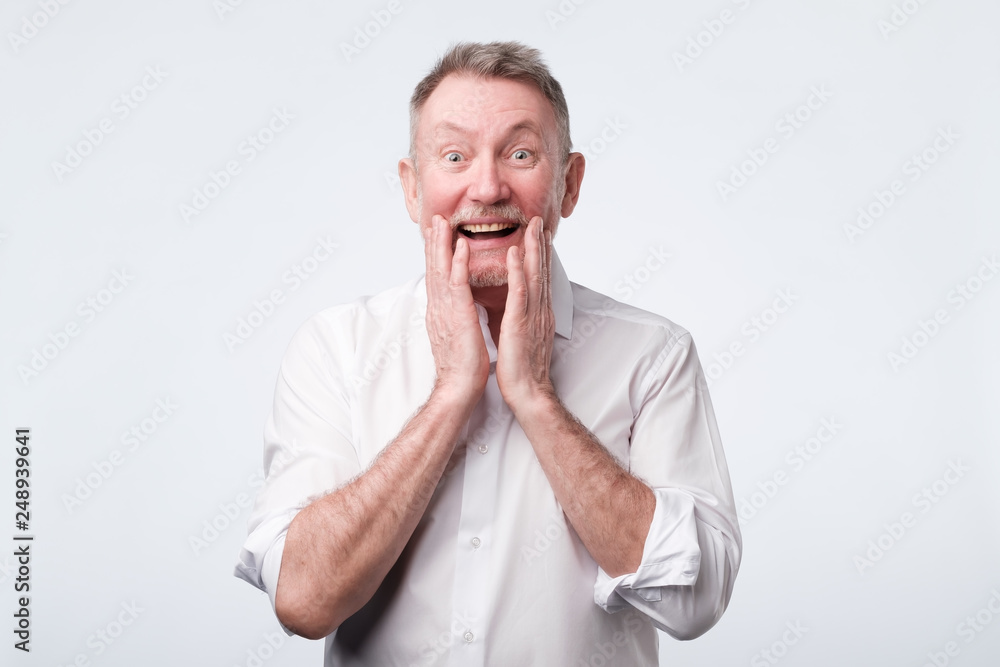 Senior man looks happy glad joyfully widely smiles like heard a good news Senior man looks happy glad joyfully widely smiles like heard a good news