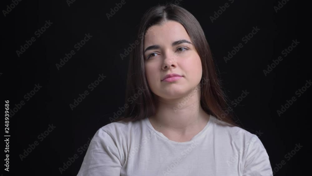 Portrait of young overweight brunette caucasian girl watching thoughtfully on black background. Portrait of young overweight brunette caucasian girl watching thoughtfully on black background.