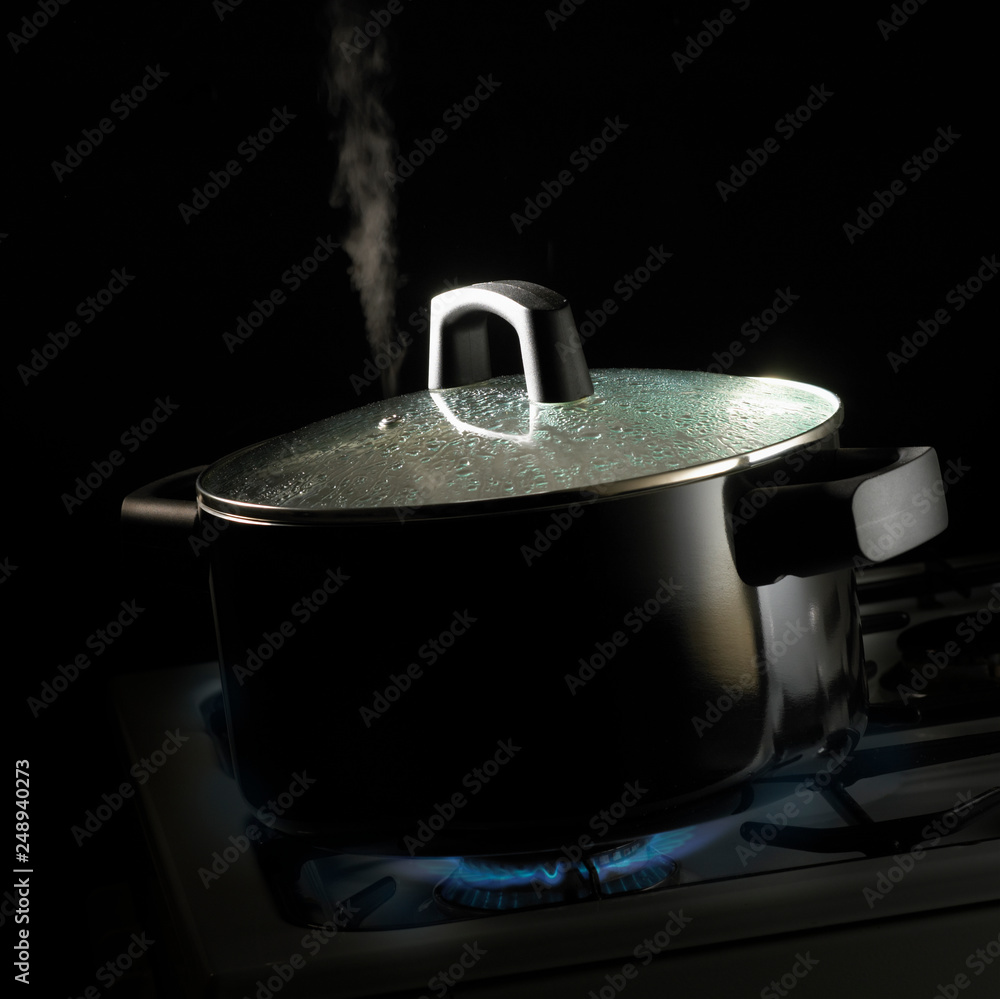 Φωτογραφία PAN OF BOILING WATER WITH CONDENSATION ON GLASS LID SIMMERING ON GAS COOKER