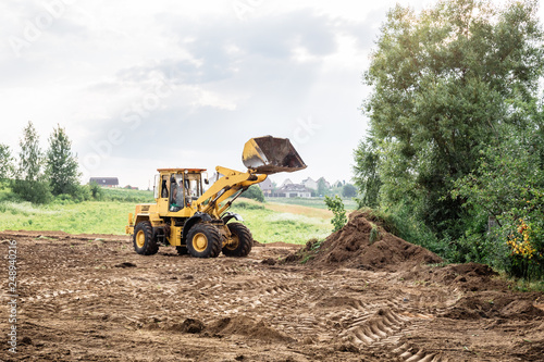 large yellow wheel loader aligns a piece of land for a new building. May be cut to banner or wallpaper with copy space.