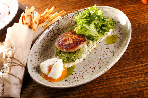 Foto Pashto egg with cutlet and salad on plate and black wood background