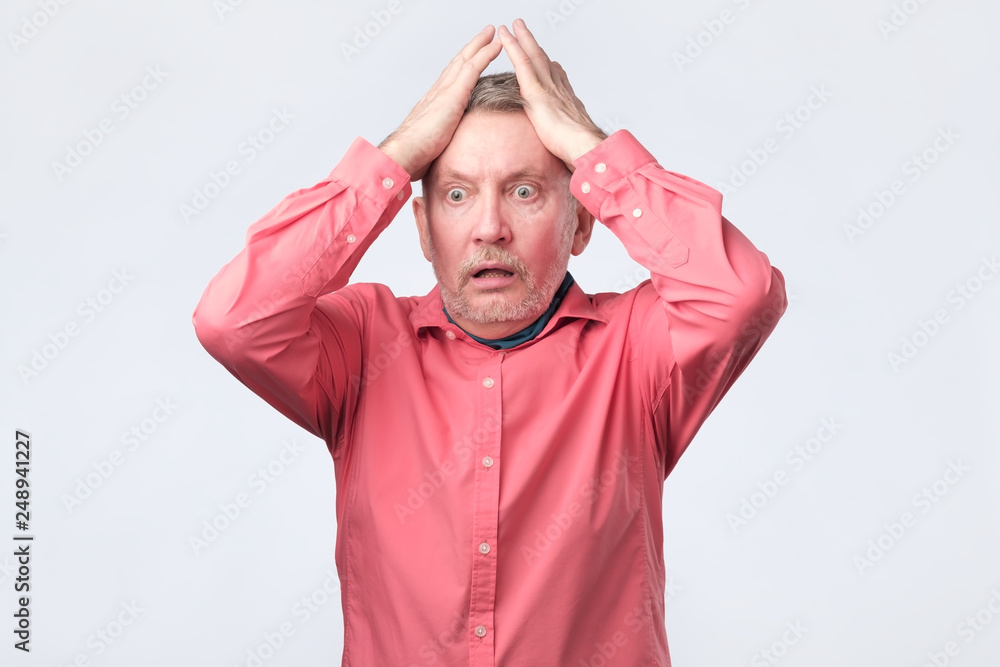 Senior angry man with hand at face on white studio wall Senior angry man with hand at face on white studio wall