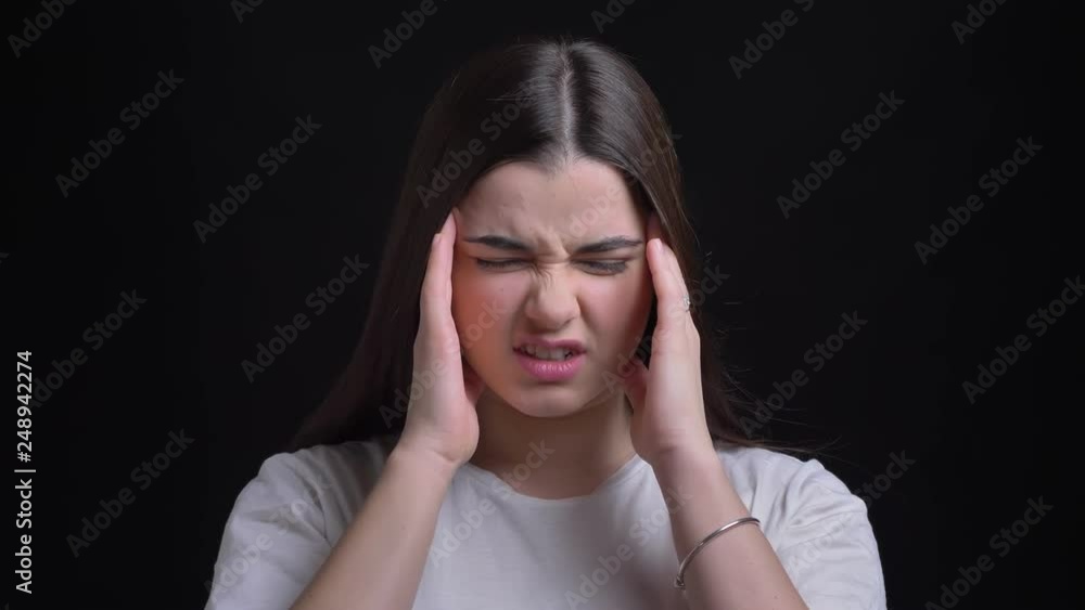 Portrait of young overweight brunette caucasian girl suffering from headache and making massage on black background. Portrait of young overweight brunette caucasian girl suffering from headache and making massage on black background.