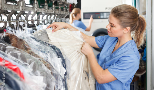 Foto worker of laundry inspecting clothes after dry cleaning