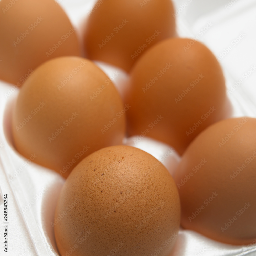 SIX BROWN EGGS IN WHITE EGG BOX IN CLOSE UP
